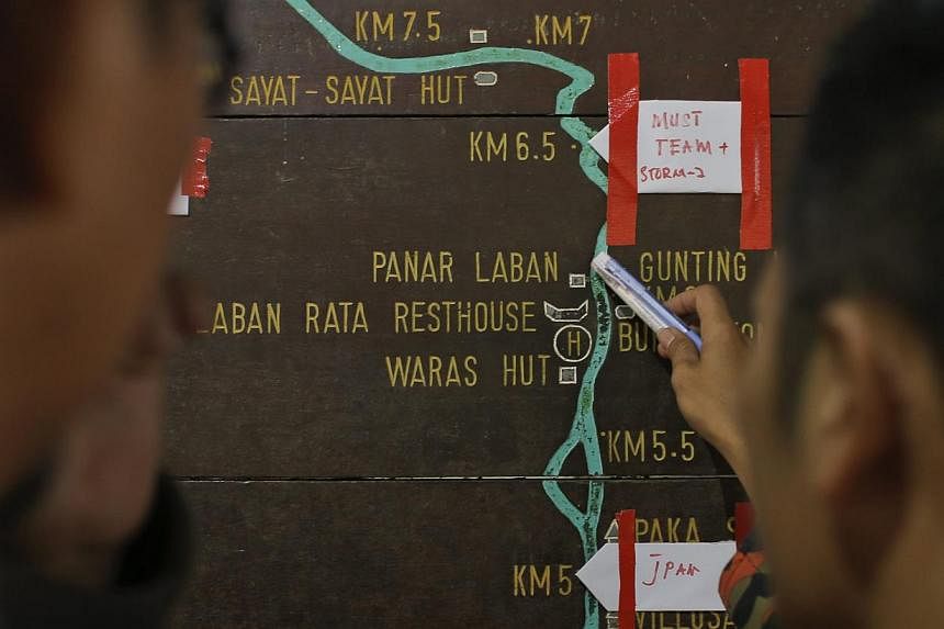 Malaysian rescue officials mark their current locations on the information board located on the way to Mount Kinabalu during a rescue mission for more than 130 climbers who were stranded on one of Southeast Asia's highest mountains after an earthquak