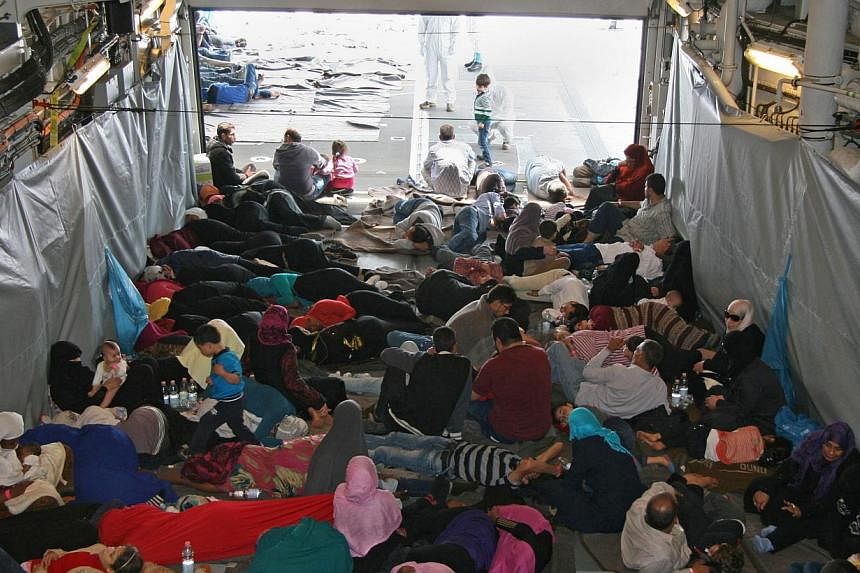 A photo provided by the German Armed Forces (Bundeswehr) shows rescued migrants sitting in the shadow on a deck of the German Navy frigate Hessen at an unspecified location in the Mediterranean Sea on June 6, 2015. -- PHOTO: EPA&nbsp;