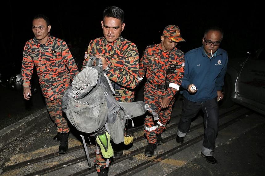ABOVE: Emotions running high at Changi Airport yesterday as parents reunited with their children who had gone to Mount Kinabalu on a school trip. LEFT: Members of a Malaysian Fire and Rescue Department team with a bag containing part of a body retrie
