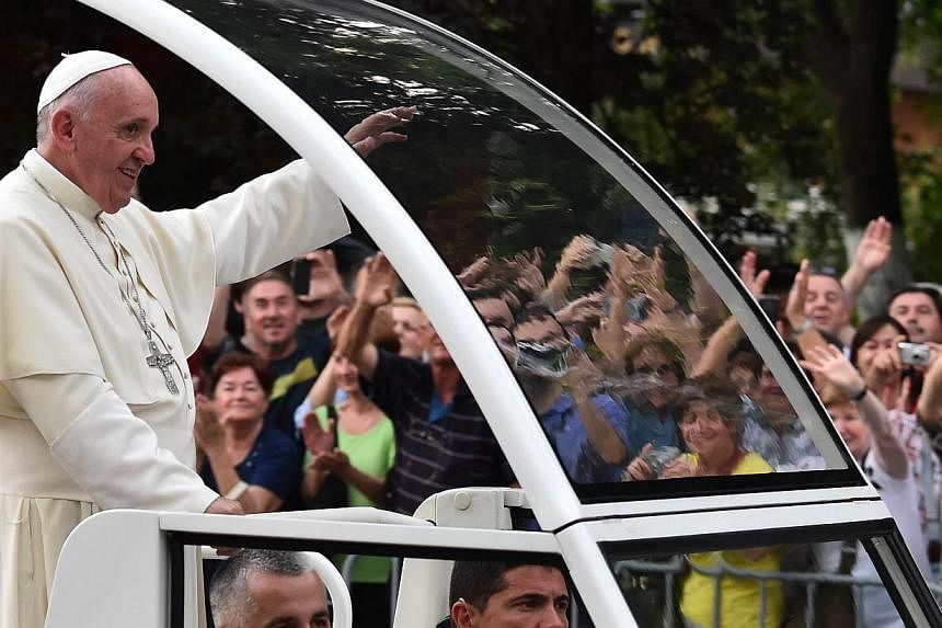 Pope Francis waves to the crowd from the popemobile on his way to an inter-religious meeting with the archbishop of Sarajevo, Cardinal Vinko Puljic, as part of a one day visit in Bosnia, on June 6, 2015 in Sarajevo. -- PHOTO: AFP