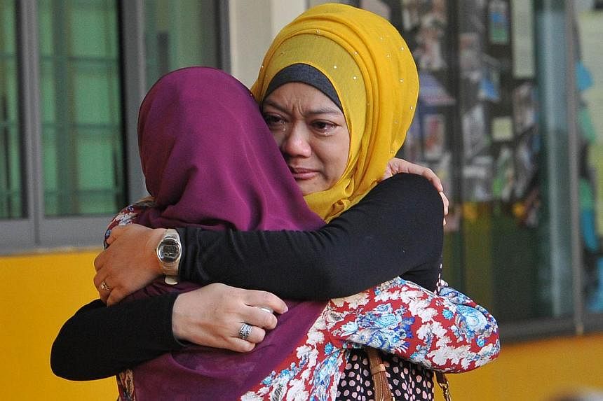 Family members of students from Tanjong Katong Primary School embrace in tears in memory of the victims from the school in an earthquake on Malaysia's Mount Kinabalu. -- PHOTO: AFP