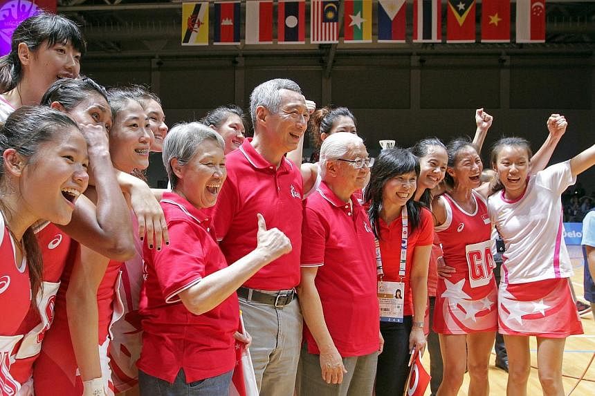 (From left) Ho Ching, Prime Minister Lee Hsien Loong and President Tony Tan Keng Yam posing for a photo with Singapore's netballers after their historic gold medal. -- ST PHOTO:&nbsp;SEAH KWANG PENG