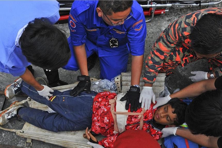 A Singapore victim being examined by personnel from Malaysia's Fire and Rescue Department and Civil Defence Department during a rescue mission in Kundasang on June 5, 2015. -- PHOTO: EPA