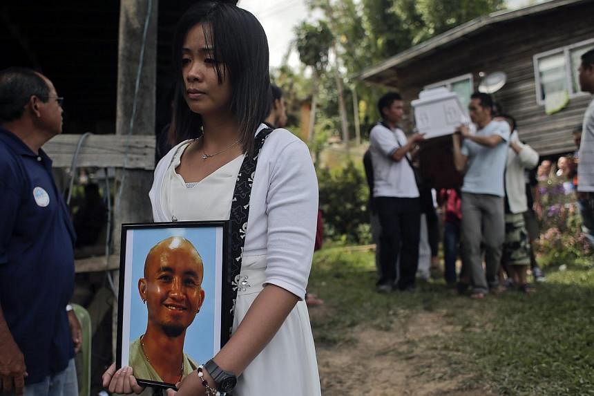 Jessica Sikta (second from left) holds a picture of her fiance Valerian Joannes, a 27-year-old tour guide who was among those killed in an earthquake which hit Sabah, during his funeral ceremony in Kundasang, Sabah, Malaysia, on June 8, 2015. -- PHOT