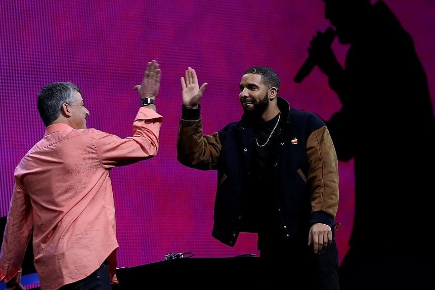 Apple's senior vice president of Internet Software and Services Eddy Cue (left) high-fives Drake during the Apple Music introduction at the Apple WWDC on June 8, 2015, in San Francisco, California. -- PHOTO: AFP
