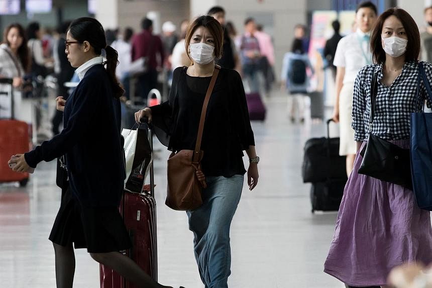 Tourists wearing face masks walk through Incheon International Airport in Incheon, South Korea, on Monday, June 8, 2015.&nbsp;To detect Mers-CoV cases early, Singapore will start temperature screening at air checkpoints for passengers arriving from S