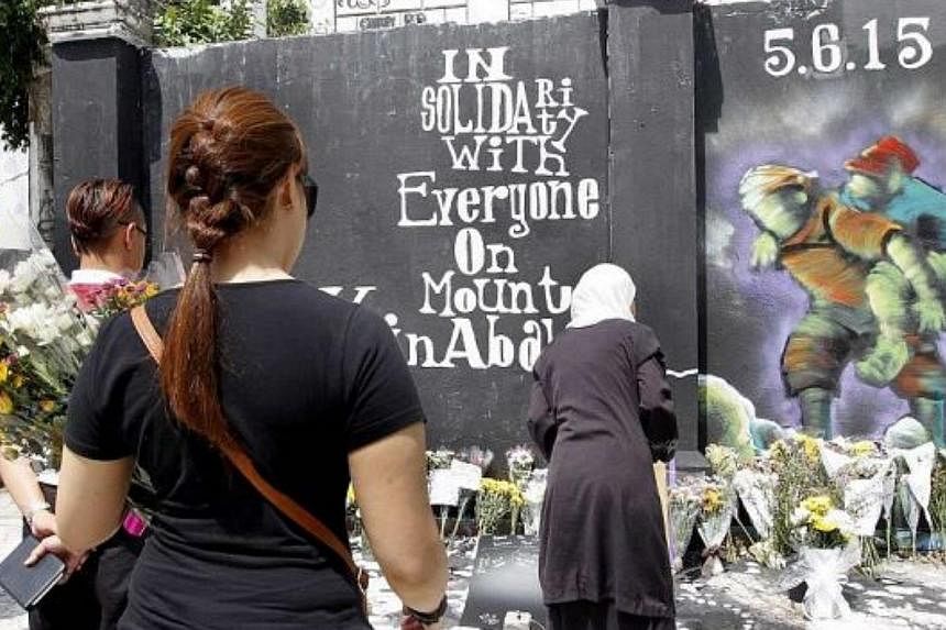 People paying their last respects to the victims of the earthquake at Mount Kinabalu at the graffiti corner of the old ruined colonial building in Kota Kinabalu. -- PHOTO: THE STAR/ASIA NEWS NETWORK