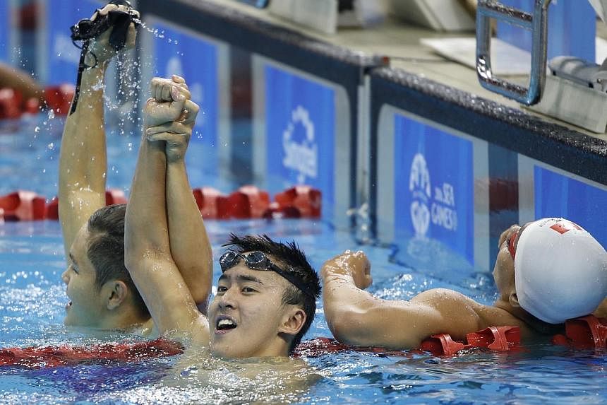 Swimmer Quah Zheng Wen (centre) raising his right hand in triumph with teammate Pang Sheng Jun (left) after winning the 400m individual medley on June 9, 2015. It was Singapore's 51st gold medal of the SEA Games, breaking the previous mark of 50 set 