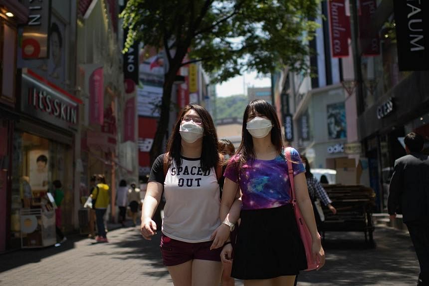 Tourists wearing face masks walk in the popular Myeongdong shopping area in Seoul on June 4, 2015.&nbsp;Taiwanese health authorities issued a travel alert to cover all of South Korea late on Tuesday, widening its caution on travel to the country stri