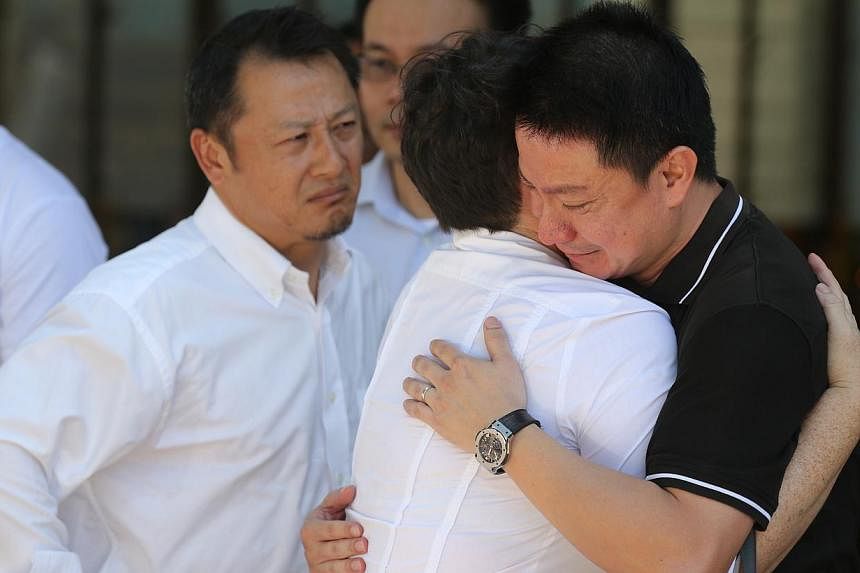 Father of Rachel Ho being comforted by family and friends. -- ST PHOTO: ONG WEE JIN