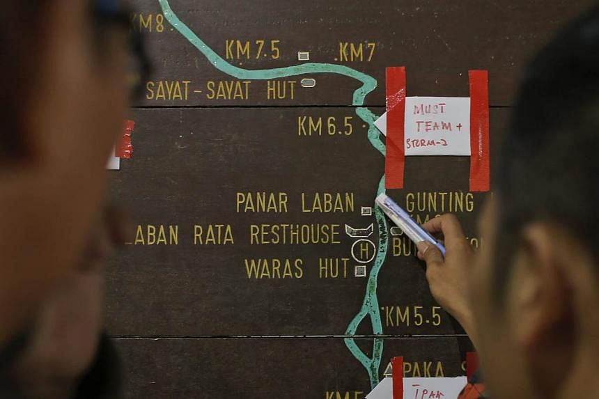 Malaysian rescue officials mark their current locations on the information board located on the way to Mount Kinabalu during a rescue mission on June 6, 2015. -- PHOTO: EPA