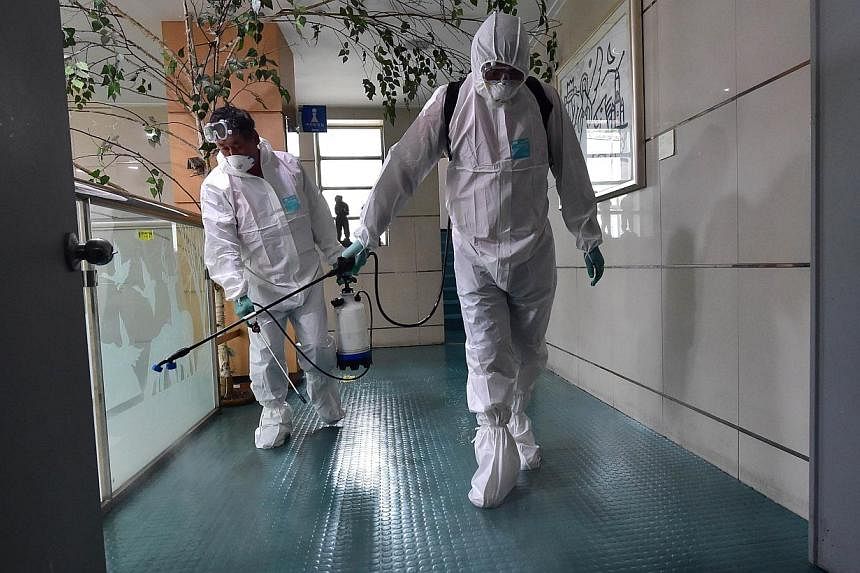 South Korean health officials spraying an antiseptic solution while wearing protective gear in an art hall in Seoul on June 12, 2015. -- PHOTO: AFP