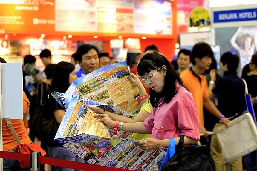 A woman looks through a tour brochure at a travel fair in Singapore. The Singapore Tourism Board announced a new licensing condition on Friday so that - from July 15 - all licensed travel agents will have to seek the decision of outbound leisure cust