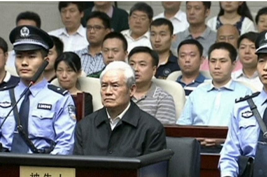 Zhou Yongkang, China's former domestic security chief, sits between his police escorts as he listens to his sentence in a court in Tianjin, China, in this still image taken from video provided by China Central Television and shot on June 11, 2015. --