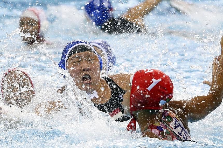 Singapore's Adelyn Yew (blue cap) tussling with Indonesia's Ayudya Suidarwanty Pratiwi (right) during their women's water polo opener on June 10, 2015. -- ST PHOTO: KEVIN LIM&nbsp;