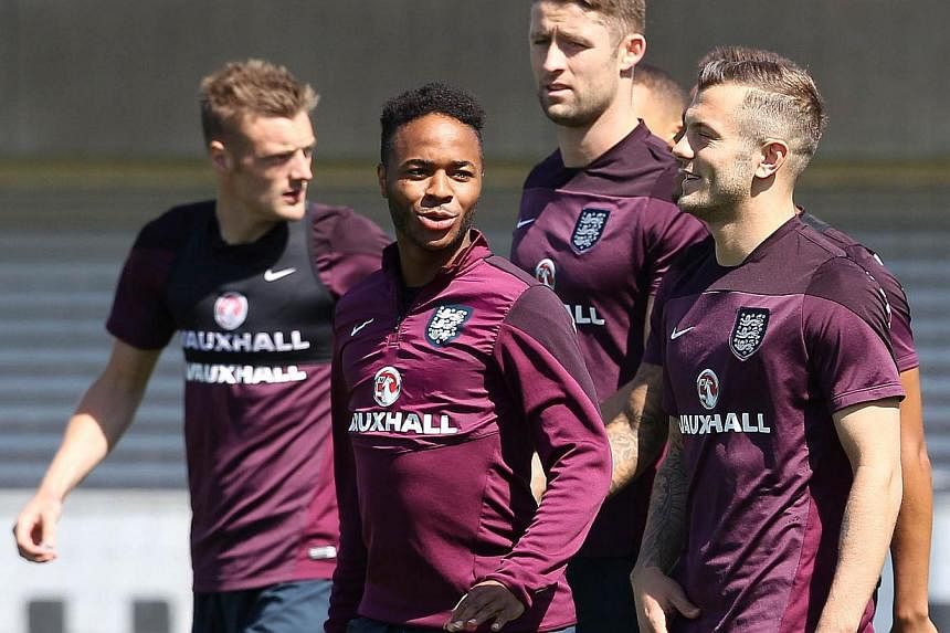 England's Raheem Sterling (centre) talks with team mate Jack Wilshere (right) during an England team training session at Saint George's Park in Burton-upon-Trent on June 4, 2015. -- PHOTO: AFP