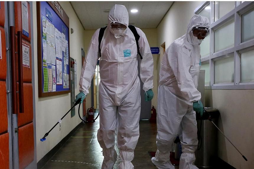 A Seoul metropolitan government worker wearing a protective suit spraying antiseptic solution inside a hallway at the Sowol Art Hall in Seoul on June 12, 2015. -- PHOTO: BLOOMBERG