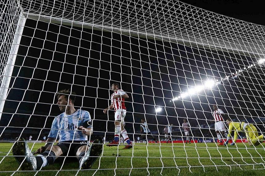 Argentina's Lionel Messi (left) sits in the net after missing a goal against Paraguay during their first round Copa America 2015 football match at Estadio La Portada de La Serena in La Serena, Chile, on June 14, 2015. -- PHOTO: REUTERS&nbsp;