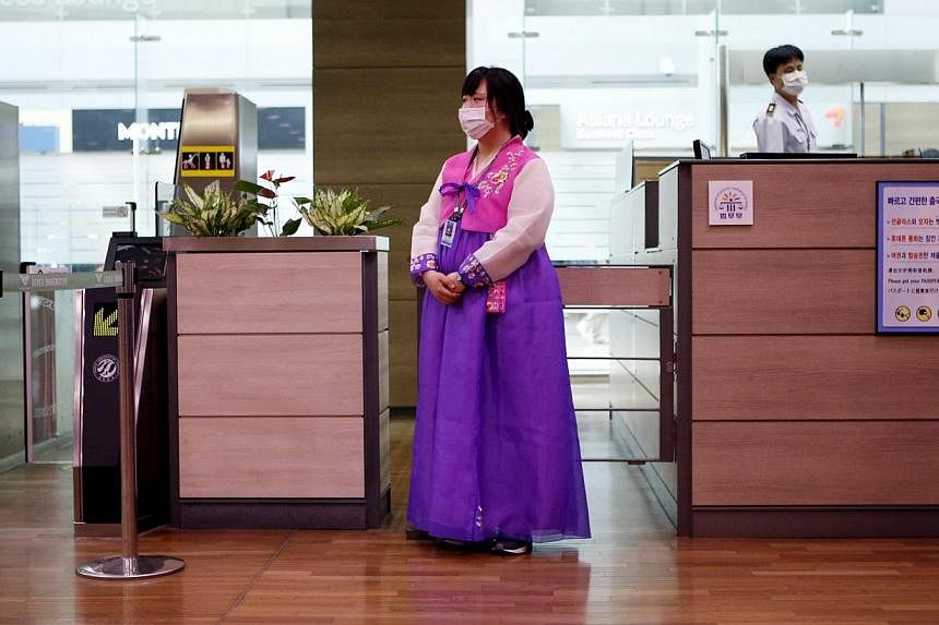 An employee dressed in a Hanbok traditional costume wears a mask to prevent contracting Middle East Respiratory Syndrome (Mers) as she stands in front of a check-in counter at the Incheon International Airport in Incheon, South Korea on June 14, 2015