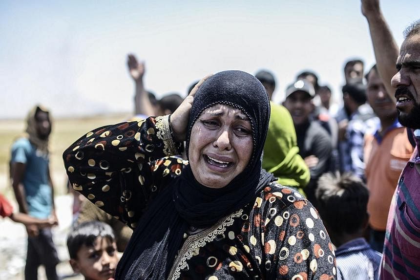 A Syrian woman cries after an airstrike hit the eastern part of the Syrian town of Tal Abyad at the Turkish crossing of Akcakale in the southeast Sanliurfa province on June 14, 2015.&nbsp;Kurdish forces pressed their advance on the strategic militant