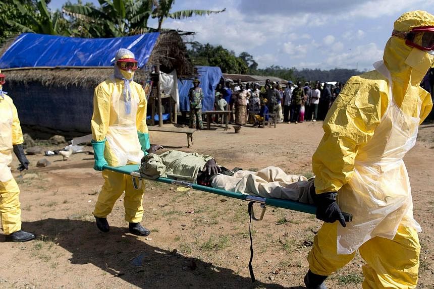 A file picture taken in Patrice near Macenta on Nov 21, 2014 shows health workers wearing protective suits carrying a patient suspected of having Ebola on their way to an Ebola treatment centre run by the French Red Cross. -- PHOTO: AFP