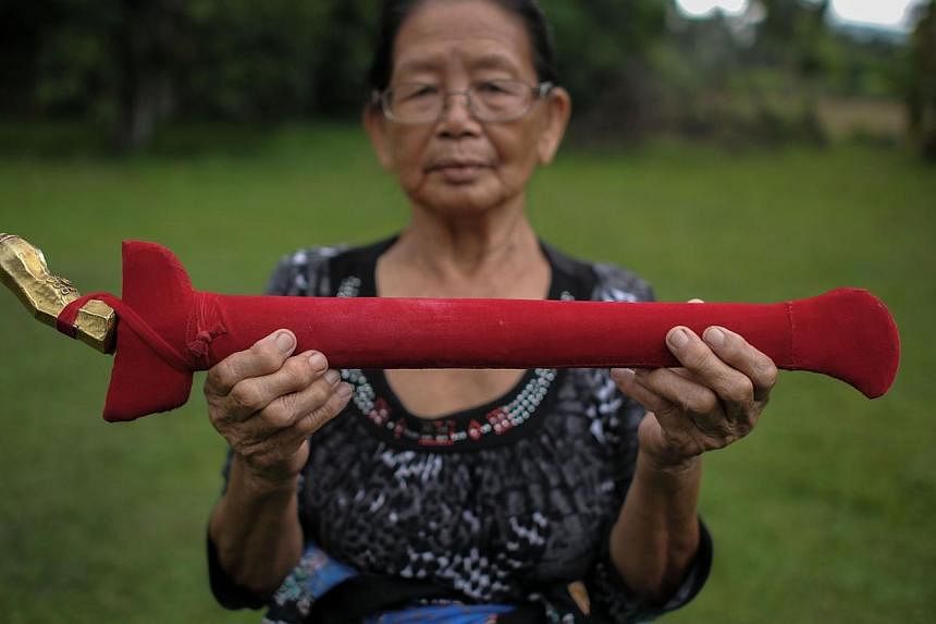 Head shaman from the Kadazan-Dusun tribe Singkaban Kowil, 75, holds a dagger called "hulu karis" at her residence in Damat, a village in the district of Tamparuli, in Malaysia's Sabah state on Borneo island on June 13, 2015, ahead of special prayers 
