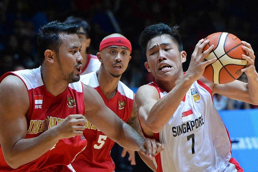 Singapore's Wu Qingde (right) attempting to fend off Indonesia's Adhipratama Putra in their men's basketball semi-final at the OCBC Arena on June 14, 2015. -- ST PHOTO: CHONG JUN LIANG &nbsp;