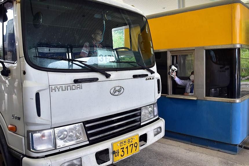 An official (right) checks the body heat of a South Korean truck driver arriving from North Korea's Kaesong Industrial Complex, at the South's CIQ (Customs, Immigration, Quarantine) gate at the inter-Korean transit office in Paju on June 13, 2015.&nb