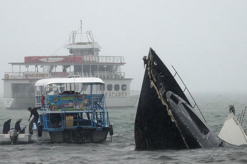 A man gets off a ferry next to two sunken yachts after hurricane Carlos in Acapulco, Guerrero State, Mexico on June 14, 2015. Hurricane Carlos was downgraded to a tropical storm Sunday off Mexico's Pacific coast, forecasters said. -- PHOTO: AFP