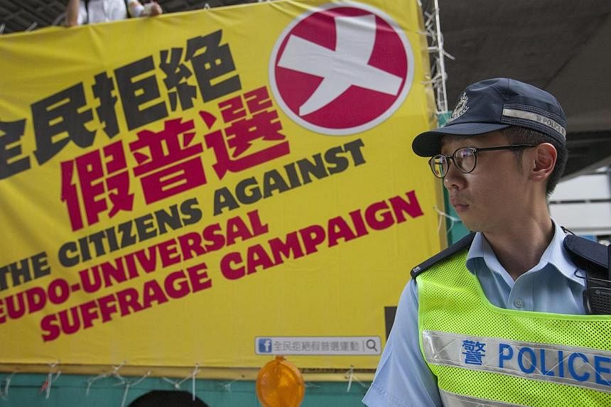 A police officer stands guard as supporters of real universal suffrage in Hong Kong march through the streets in Hong Kong, China, on June 14, 2015. Hong Kong police said on Monday that they had made arrests after discovering "suspected" explosives, 
