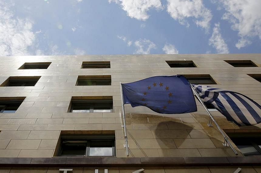 A European Union flag (left) and a Greek national flag flutter at the entrance of the Bank of Greece headquarters in Athens on June 11, 2015.&nbsp;The collapse of talks between Greek ministers and their bailout creditors and a slide in Wall Street le