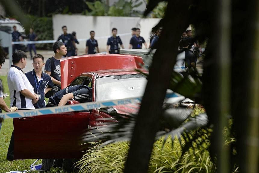 Singapore police officers inspect a red sedan car with a bullet hole on the windscreen which was involved in an early morning shooting incident after it illegally bypassed a police vehicular checkpoint, on May 31, 2015.&nbsp;One of the passengers in 