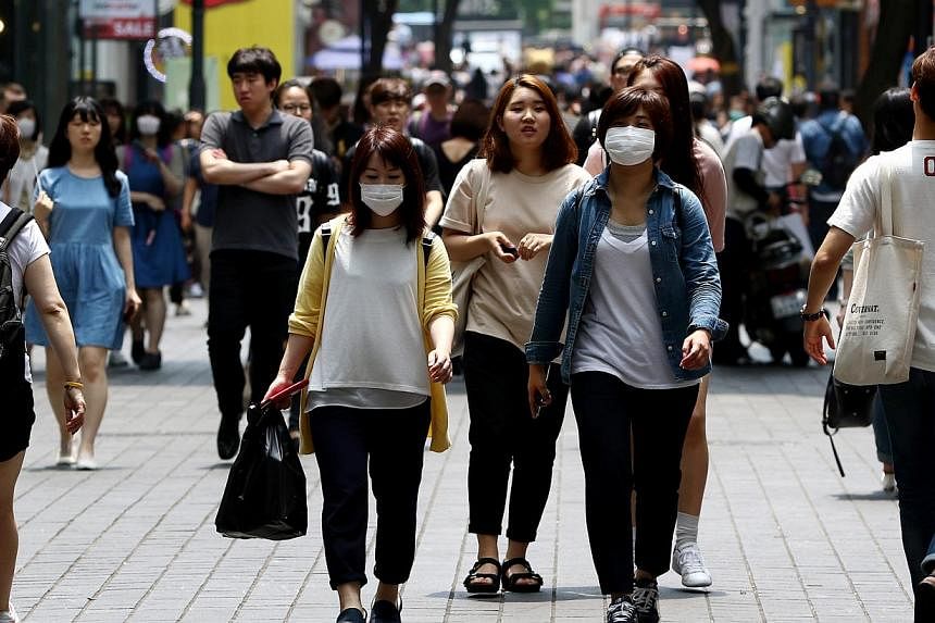 Pedestrians wearing masks walk through the Myeongdong shopping district of Seoul, South Korea, on Monday, June 15, 2015. -- PHOTO: BLOOMBERG&nbsp;