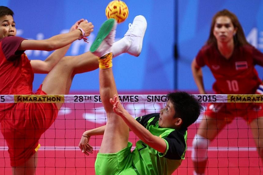 Thailand's Masaya Duangsri (left) and Myanmar's Wai Khin Hnin (centre) in action, as Thailand's Somruedee Pruepruk (right) watches, during the sepak takraw women's doubles finals.&nbsp;Thailand retained their SEA Games sepak takraw gold medal in the 