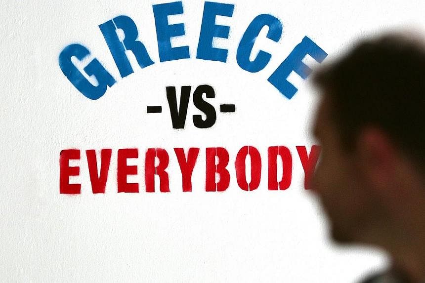 A man looks at a graffiti reading "Greece vs Everybody" on a wall in central Athens on June 11. -- PHOTO: AFP