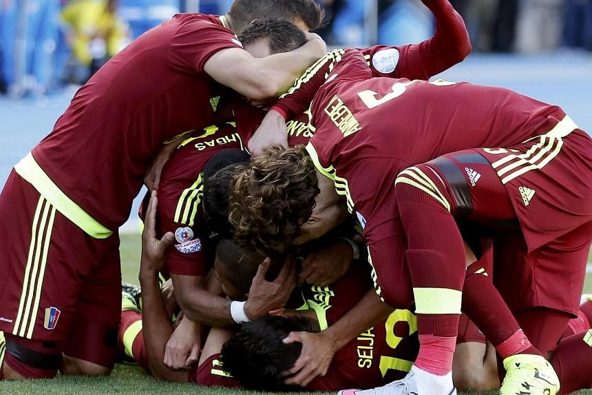 Venezuela players mob teammate Jose Rondon (obscured) as they celebrate his goal against Colombia during their first round Copa America 2015 soccer match at Estadio El Teniente in Rancagua, Chile on Sunday. -- PHOTO: REUTERS