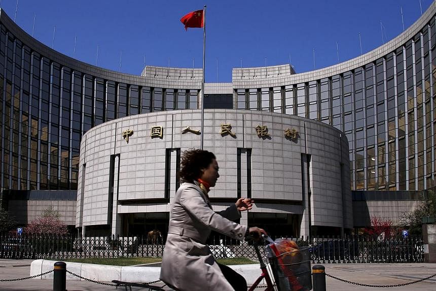 A woman rides past the headquarters of the People's Bank of China in Beijing on April 3, 2014. China will allow private investment funds to trade in the country's interbank debt market for the first time, a central bank document dated June 15 and obt