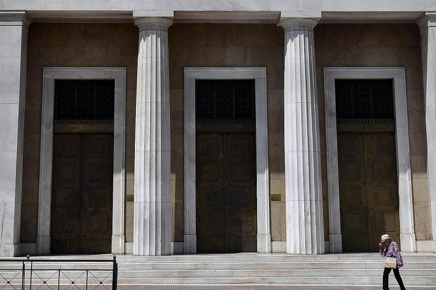 A woman walks past Bank of Greece headquarters in central Athens on June 15, 2015. Asian stocks fell as investors awaited an update from the Federal Reserve on US monetary policy and a meeting of euro-area finance ministers with Greece. -- PHOTO: AFP