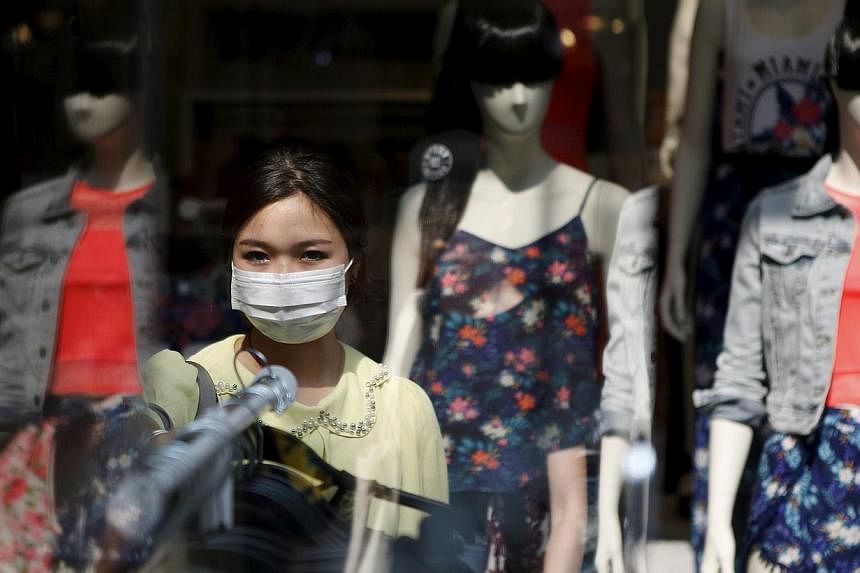 A woman wearing a mask to prevent contracting Middle East Respiratory Syndrome (MERS) shops at a clothing store in central Seoul, South Korea, on June 15, 2015. -- PHOTO: REUTERS