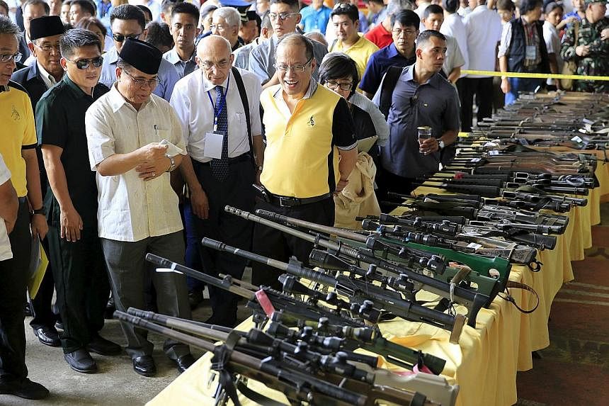 Philippine President Benigno Aquino (front right) and Al-haj Murad Ebrahim (front third right), chairman of the Moro Islamic Liberation Front (MILF), look at weapons during the Ceremonial Turnover of Weapons and Decommissioning of MILF Combatants on 