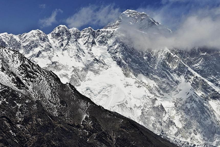 This photograph taken on April 20, 2015, shows a view of Mount Everest (centre, top) towering over the Nupse-Lohtse massif (foreground) from the village of Tembuche in the Khumbu region of northeastern Nepal. Mount Everest, moved three centimetres to