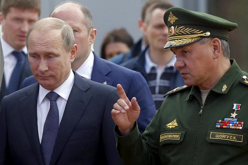 Russian President Vladimir Putin (left) listens to Defence Minister Sergei Shoigu as they arrive for the opening of the Army-2015 international military forum in Kubinka, outside Moscow, Russia, June 16, 2015. -- PHOTO: REUTERS