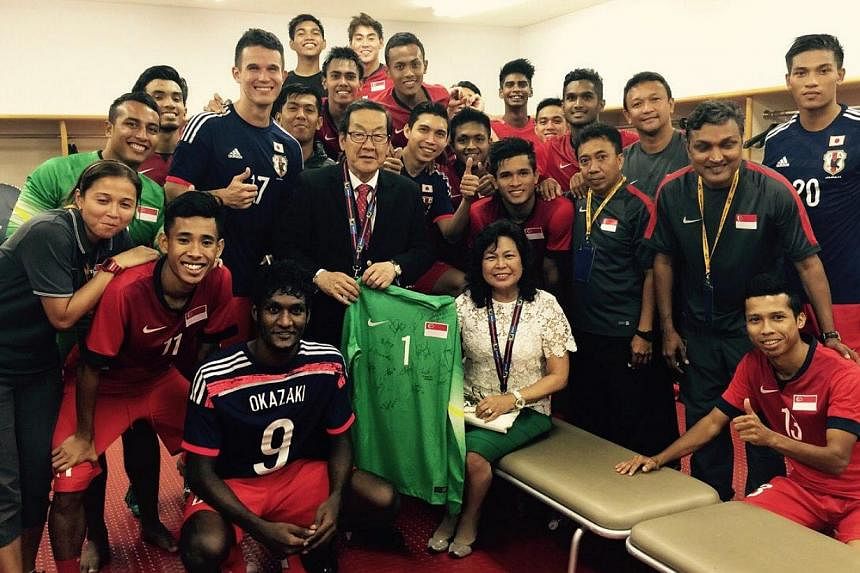 Singapore's Ambassador to Japan Chin Siat Yoon (holding goalkeeper Izwan Mahbud's jersey) and his wife Wang Lee Moi (seated) &nbsp;with the Lions in their dressing room after the 0-0 World Cup qualifying draw with Japan. -- PHOTO: COURTESY OF CHIN SI