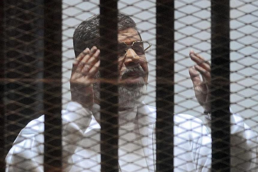 Former Egyptian president Mohamed Mursi gesturing in a cage in the courtroom where he stands charged of spying with Qatar, in Cairo, Egypt, on Feb 15, 2015. An Egyptian court sentenced Mursi to death on Tuesday, June 16, in a case related to a 2011 m