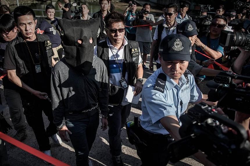 A suspect is escorted by policemen during a crime reconstruction in the east-coast district of Sai Kung in Hong Kong on June 16, 2015 a day after suspected explosives were seized at an abandoned television studio.&nbsp;China on Tuesday warned against