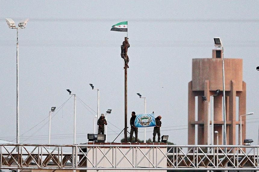 A picture taken from the Turkish side of the border between Turkey and Syria shows members of Free Syrian Army hoisting a flag near the Syrian-Turkish border line in Akcakale, Sanliurfa province, south-eastern Turkey on June 16, 2015. -- PHOTO: EPA