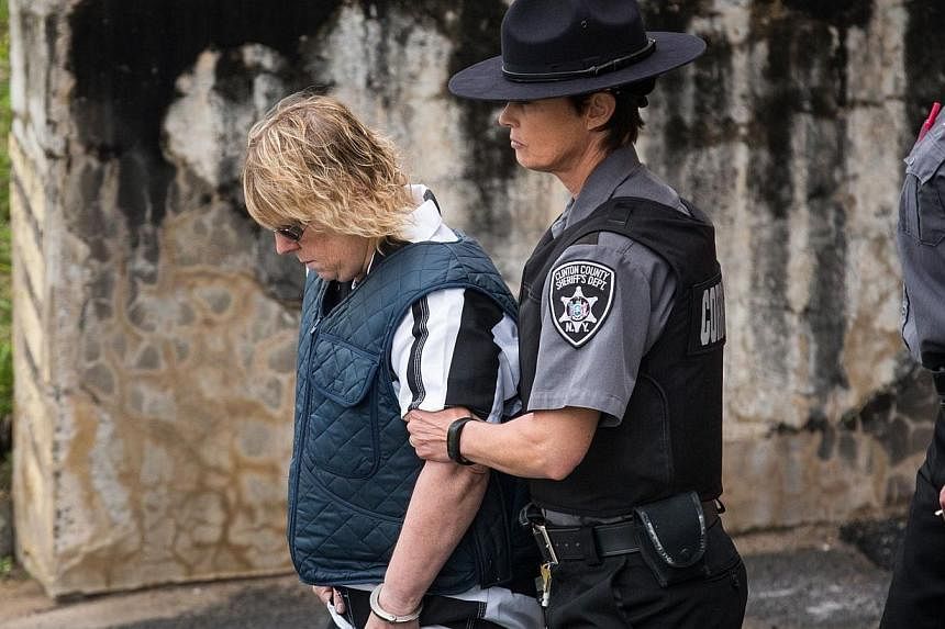 Joyce Mitchell (left), a prison worker who allegedly helped two convicts escape from prison, is lead from Plattsburgh Ciy Court after a hearing on Monday in Plattsburgh, New York. -- PHOTO: AFP