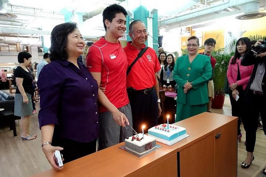 (Right) Joseph Schooling, seen here with his parents May and Colin Schooling, getting a birthday surprise in the ST newsroom with cakes from ST and the Eurasian Association yesterday, as the association's second vice-president Yvonne Pereira (in gree