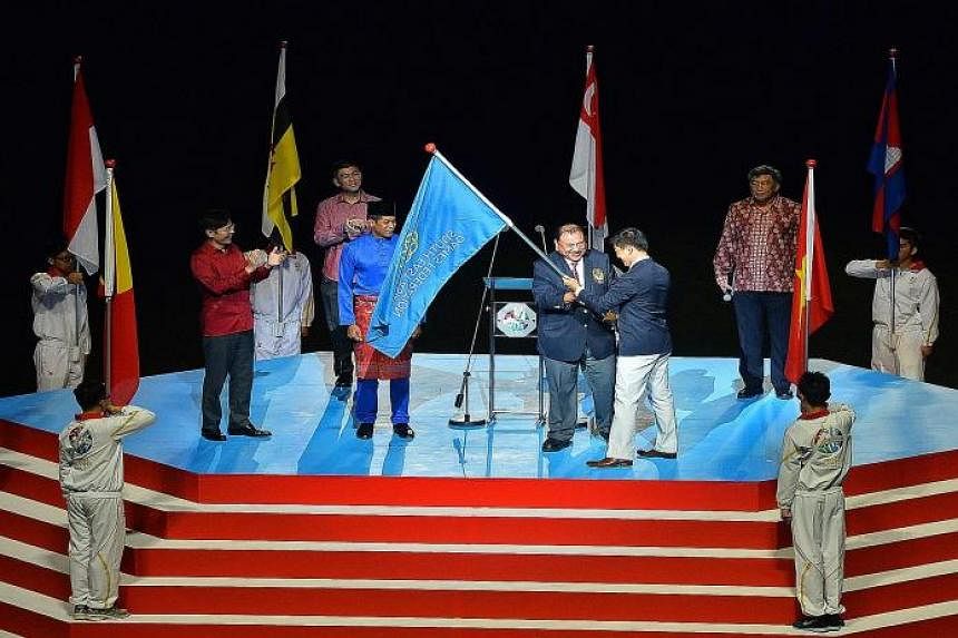 Tunku Imran, president of the Olympic Council of Malaysia, receiving the SEA Games Federation flag from Singapore National Olympic Council president Tan Chuan-Jin last night.