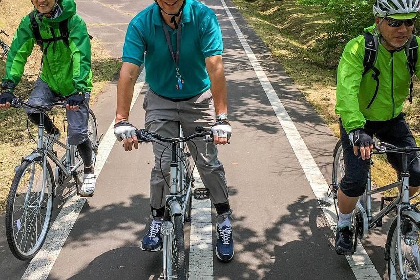 Mr Lee Hsien Loong, with two of his guides during his cycling trip in Kushiro, Hokkaido, on Tuesday. The cycling trail is a disused railroad track. PM Lee said this was a "possibility for our Rail Corridor". In its request for proposals in March to d